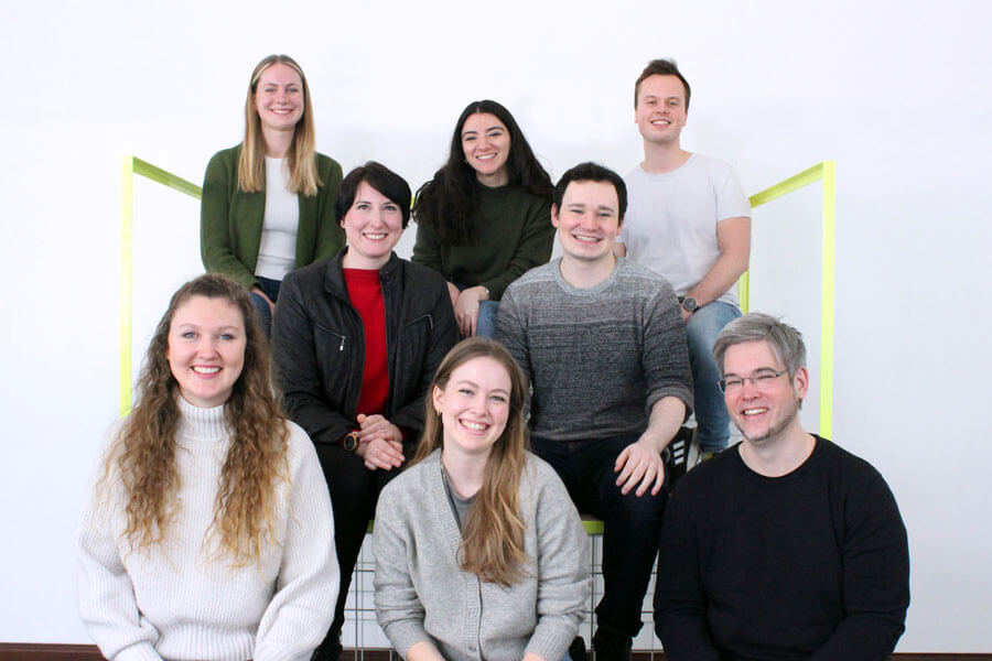 This is a picture of the SUMM team. Eight people are standing in front of the camera and smiling. There are three men and five women.