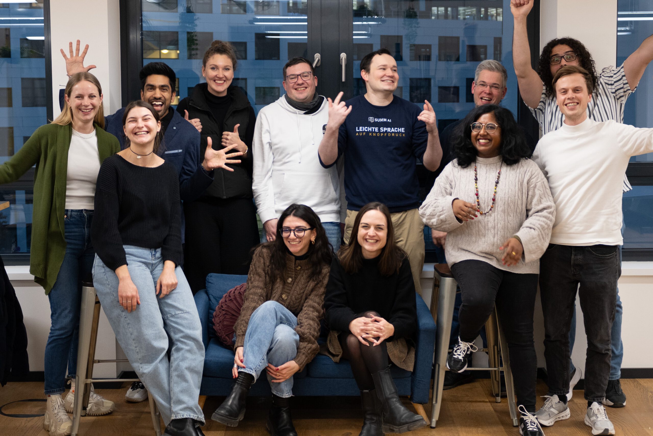 Das ist ein Bild vom Team von SUMM. Acht Personen lachen für die Kamera. Es gibt drei Männer und fünf Frauen.