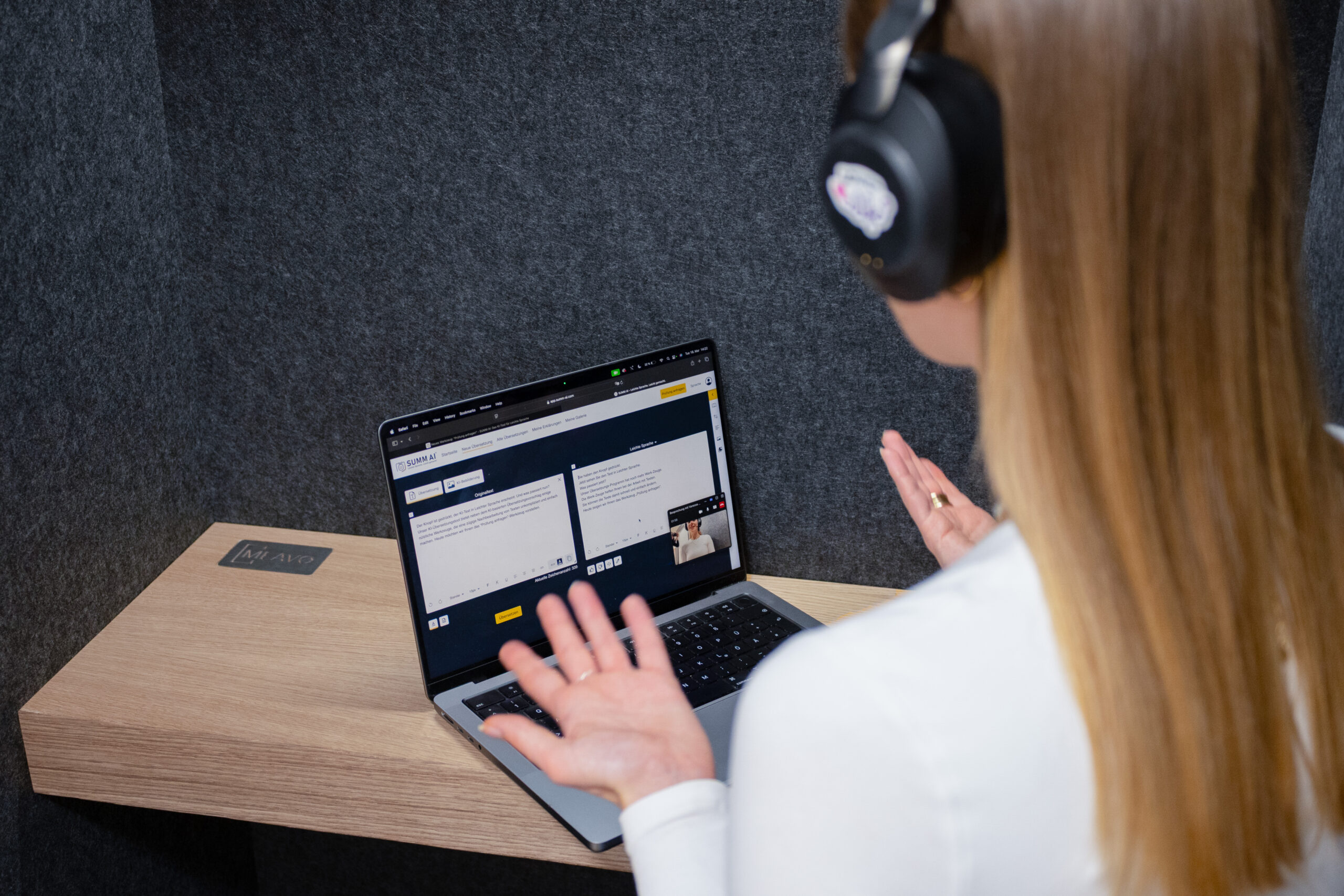 Foto Übersetzung Eine Mitarbeiterin von SUMM AI sitzt mit dem Rücken zur Kamera vor einem aufgeklappten Laptop und nutzt das Übersetzungs-Tool. Sie trägt Kopfhörer.