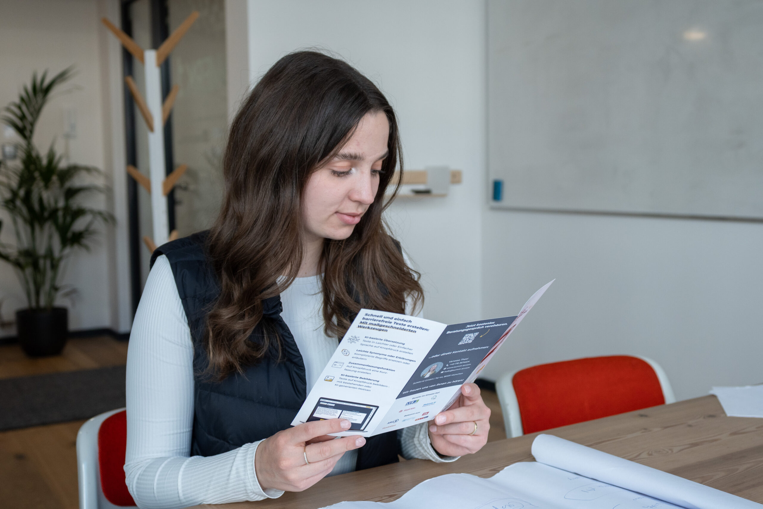 Foto Broschüren-Prüfung Eine Mitarbeiterin von SUMM AI, die in den Büroräumen die neueste Broschüre der Firma prüft.