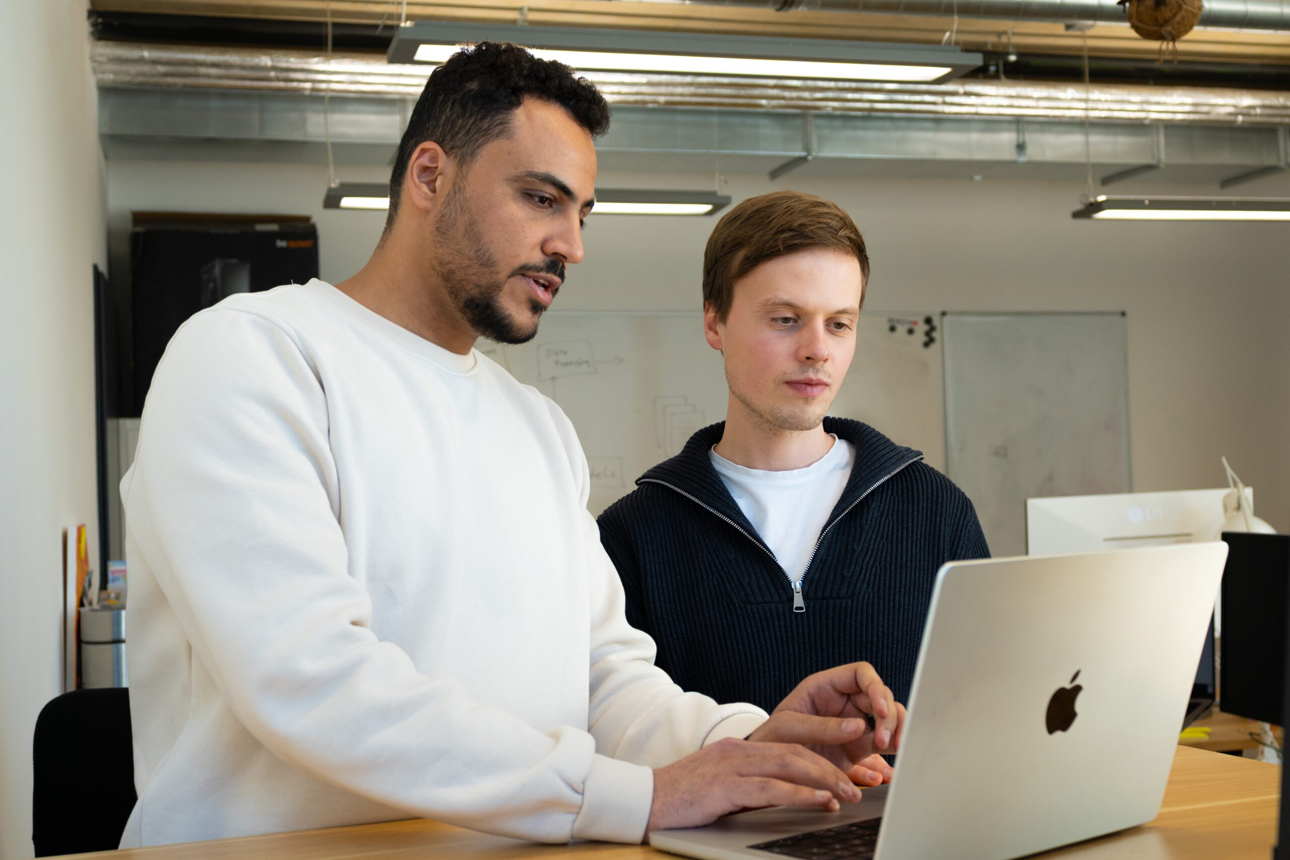 leichte-sprache-wichtig-zielgruppe-pruefgruppe-erklaerung Zwei Menschen sitzen an einem Tisch. Auf dem Tisch ist ein Laptop. Ein Mensch tippt auf dem Laptop etwas ein. Der Laptop zeigt die Webseite von SUMM und das Übersetzungstool. Wir blicken hier von hinten wie die zwei Menschen auf den Laptop.
