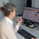 Hier sieht man eine Redakteurin vor einem Monitor. Auf dem Monitor ist eine Seite in Leichter Sprache zu sehen.