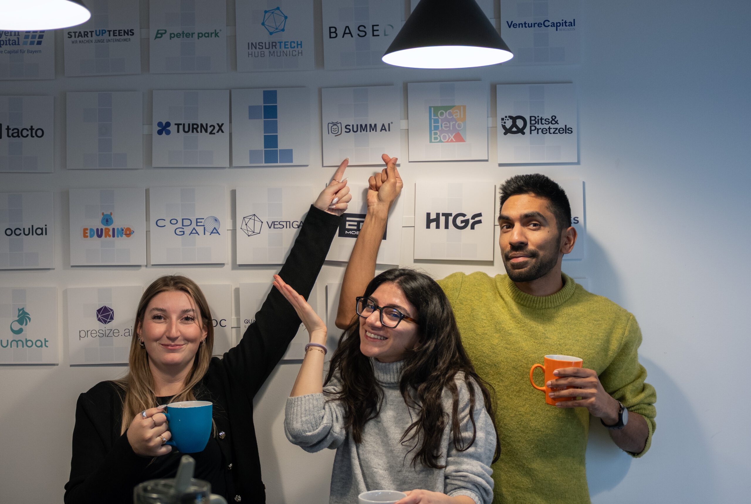 Das ist ein Bild vom Team von SUMM. Acht Menschen stehen vor der Kamera und lächeln. Es sind drei Männer und fünf Frauen.